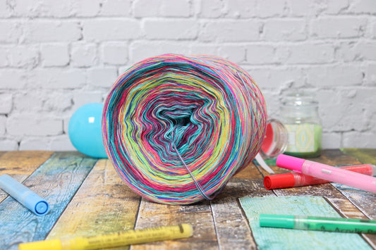 Auf dem Bild kann man den Bobbel "Berechenbare Bohemian" erkennen. Als Dekoration sind bunte Stifte, sowie verschiedene bunte Kerzen zu sehen auf deinem bunten Hintergrund.